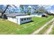 Exterior view of the white home with metal roof and green lawn on a partly cloudy day at 6673 146Th N Ave, Clearwater, FL 33764