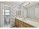 Bathroom featuring patterned wallpaper, a large mirror, and a vanity with wooden cabinets at 7035 Drury St, Tampa, FL 33635