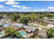 Aerial view of a property showcasing a backyard pool and patio, mature trees, and fenced yard in a tranquil setting at 8497 Portulaca Ave, Seminole, FL 33777