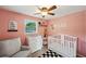Cozy bedroom with pink walls, a crib, a changing table, and a ceiling fan, designed for a  at 8497 Portulaca Ave, Seminole, FL 33777