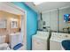 Functional laundry room with a washer, dryer, and adjoining half bathroom, featuring blue accent walls at 8497 Portulaca Ave, Seminole, FL 33777