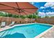 In-ground pool surrounded by lounge chairs, with an umbrella for shade at 8497 Portulaca Ave, Seminole, FL 33777