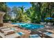 Bright community pool with lounge chairs and blue umbrellas surrounded by mature trees at 8562 Acorn Ridge Ct, Tampa, FL 33625