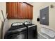 Convenient laundry room equipped with a washer, dryer, and wood cabinets for storage at 8562 Acorn Ridge Ct, Tampa, FL 33625
