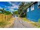 Driveway leads to garage near blue house with wooden and metal fences and a lush, green tree-filled background at 902 W Columbus Dr, Tampa, FL 33602