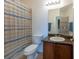 Well-lit bathroom featuring a vanity with granite countertops and a shower with a blue-striped curtain at 10522 Sky Flower Ct, Land O Lakes, FL 34638