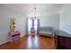 Charming Bedroom featuring hardwood floors, a gray crib, a rocking chair, and a delightful pink chandelier at 10522 Sky Flower Ct, Land O Lakes, FL 34638