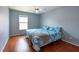 Comfortable bedroom with a ceiling fan, hardwood floors, a window and stylish blue bedding that creates a relaxing retreat at 10522 Sky Flower Ct, Land O Lakes, FL 34638
