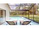 Inviting pool area with lounge chairs and lush green surroundings visible through the enclosure at 11368 Copley Ct, Spring Hill, FL 34609