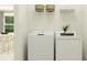 Bright laundry room features a modern washer and dryer, with shelving and decorative baskets at 11809 Sparkling Topaz Cv, Parrish, FL 34219