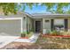 Welcoming front entrance with a solid door, a well-manicured garden bed, and an attached two-car garage at 13643 Tramore Dr, Odessa, FL 33556