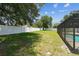 Large backyard featuring a beautiful lush green lawn, a screened-in pool and a white fence at 13835 Pathfinder Dr, Tampa, FL 33625