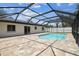A screened-in pool with light blue water is surrounded by a brick patio and green grass next to the house at 13835 Pathfinder Dr, Tampa, FL 33625