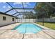 A screened-in pool with light blue water is surrounded by a brick patio and green grass next to the house at 13835 Pathfinder Dr, Tampa, FL 33625
