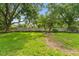 Manicured backyard with green lawn, trees, and partial wall at 15615 Indian Queen Dr, Odessa, FL 33556