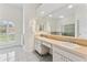 Bright bathroom with a dual sink vanity, a large mirror, and a view from the window at 15615 Indian Queen Dr, Odessa, FL 33556