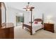Bright bedroom with a four-poster bed, ceiling fan, and sliding doors to the pool area at 15615 Indian Queen Dr, Odessa, FL 33556