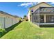 Side view of the screened-in lanai adjacent to the expansive, meticulously maintained lawn enclosed by a white fence at 17510 Bright Wheat Dr, Lithia, FL 33547