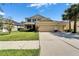 Two-story tan home with a three-car garage, manicured lawn, and palm trees at 17510 Bright Wheat Dr, Lithia, FL 33547