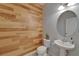 Stylish half bathroom featuring wood-paneled wall and modern pedestal sink at 17510 Bright Wheat Dr, Lithia, FL 33547