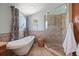 Well lit bathroom featuring a soaking tub with shower and round window at 1963 Edgewater Dr, Clearwater, FL 33755