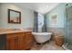Bright bathroom featuring a soaking tub, glass shower, and marble countertops with under sink wood cabinet at 1963 Edgewater Dr, Clearwater, FL 33755