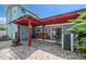 Charming backyard patio with red pergola, stone pavers, seating, and tropical foliage at 1963 Edgewater Dr, Clearwater, FL 33755