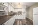 Well-lit kitchen featuring white cabinets, stone countertops, tile backsplash, appliances, and wood-look flooring at 2002 Australia E Way # 66, Clearwater, FL 33763