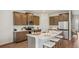 Modern kitchen with stainless steel appliances, white countertops, island with seating and brown cabinets at 2286 Sienna Spruce St, Wesley Chapel, FL 33543