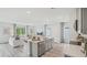 Open-concept living room showcasing a modern design with grey wood floors, stainless steel appliances, and natural light at 32702 Winterwood Blvd, Wesley Chapel, FL 33543
