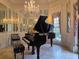 An elegant music room highlights a grand piano, chandelier, and decorative wall mirrors at 5002 S Shore Crest Cir, Tampa, FL 33609