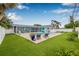 Expansive backyard featuring a pool, covered patio, manicured lawn, and tropical landscaping at 5080 43Rd S St, St Petersburg, FL 33711