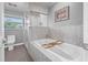 Bright bathroom featuring a soaking tub with marbled tile surround and a glass-enclosed shower at 5080 43Rd S St, St Petersburg, FL 33711