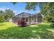 Backyard featuring a screened-in pool area, lush lawn, and mature landscaping at 5101 Hartwell Loop, Land O Lakes, FL 34638
