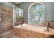 Bright bathroom featuring a tiled tub, glass shower, and large window overlooking the landscape at 5101 Hartwell Loop, Land O Lakes, FL 34638