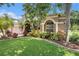 Lush front yard featuring healthy green grass and well-maintained landscaping with tropical trees and flowering plants at 5101 Hartwell Loop, Land O Lakes, FL 34638