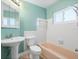 This bathroom features a pedestal sink, tiled walls, peach colored bathtub and shower head at 5108 Commonwealth Rd, Palmetto, FL 34221
