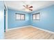 This cozy bedroom features a ceiling fan, light blue walls, wood-look floors and two windows with wood blinds at 5108 Commonwealth Rd, Palmetto, FL 34221