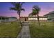 Charming home exterior with palm trees and a walkway, all set against a backdrop of a gorgeous pink sunset sky at 5108 Commonwealth Rd, Palmetto, FL 34221