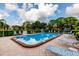 Community swimming pool surrounded by lounge chairs, manicured hedges, and lush green trees at 5623 80Th N St # 504, St Petersburg, FL 33709