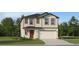 Charming two-story home with neutral siding, brown accents, a red front door, and an attached two-car garage at 5627 Red Kite Dr, Wimauma, FL 33598