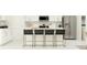 Bright, modern kitchen with white cabinets, stainless steel appliances, and island seating with black stools at 5627 Red Kite Dr, Wimauma, FL 33598
