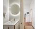 Stylish half bathroom with a unique gold circular mirror, textured wall, and modern design at 6212 Nimes Ct, Lutz, FL 33558