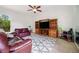 Comfortable living room with a large TV, wooden entertainment center, and modern patterned rug at 6212 Nimes Ct, Lutz, FL 33558