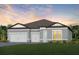 Charming single-story home featuring a three-car garage, and beautifully landscaped front yard with colorful flowers at 6811 Jared Oaks Dr, Wesley Chapel, FL 33545