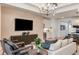 Stylish living room with a large screen TV, modern decor, and comfortable seating flowing into the kitchen area at 6811 Jared Oaks Dr, Wesley Chapel, FL 33545
