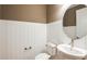Elegant powder room with white wainscoting, a round mirror, and modern fixtures at 6811 Jared Oaks Dr, Wesley Chapel, FL 33545