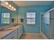 Bathroom featuring double sink vanity, a large mirror, and a tiled shower at 6913 Park Strand Dr, Apollo Beach, FL 33572