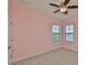 Comfortable bedroom painted pink, features two windows, and a ceiling fan at 6913 Park Strand Dr, Apollo Beach, FL 33572