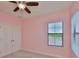 Pink bedroom features a ceiling fan, a window with blinds, and a double door closet at 6913 Park Strand Dr, Apollo Beach, FL 33572